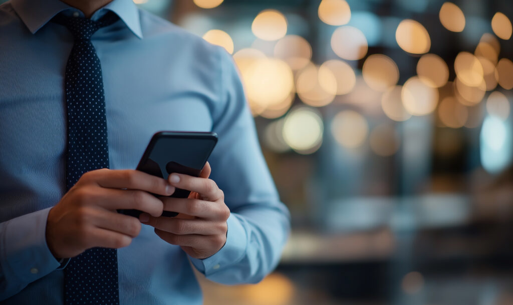 A man texting on his cellphone with blurred lights in the background, representing the advice provided by the Toronto business litigation lawyers at Milosevic & Associates in director and officer liability matters.