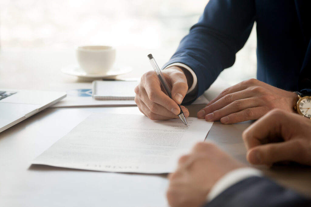 Two businessmen at a table signing a contract, representing complex commercial contract disputes and the commercial litigation services provided by Milosevic & Associates in Toronto.