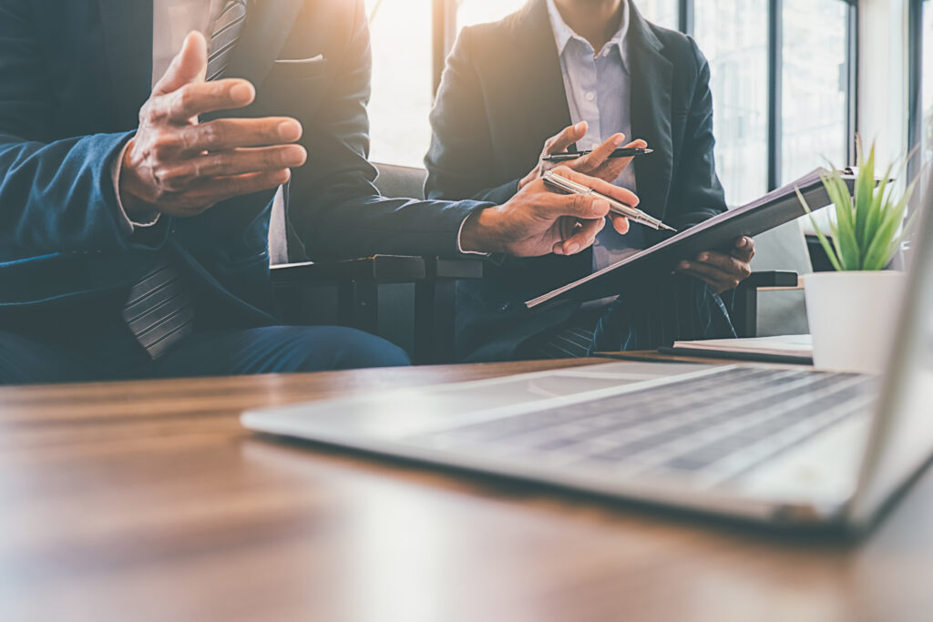 Two businessmen looking at a laptop and reviewing documents together, representing the Toronto fraud litigation lawyers at Milosevic & Associates and the legal solutions they offer in cases involving investment advisor and broker fraud.