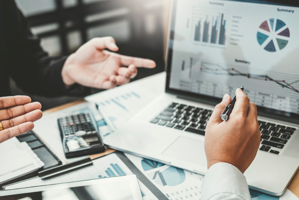 Two business colleagues reviewing financial graphs and spreadsheets together on a laptop screen, representing the debt collection enforcement and commercial creditor-debtor litigation services provided by Milosevic & Associates in Toronto.