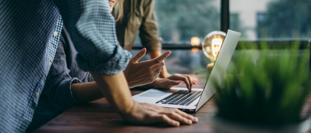 Two people working together on a laptop on a wooden desk, representing the oppression remedy and shareholder oppression claims, advised upon by the commercial litigation lawyers at Milosevic & Associates in Toronto.