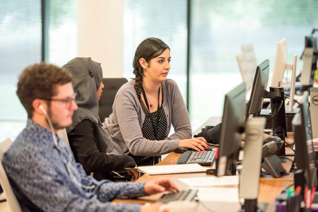 A group of young work colleagues working together at their desktop computers, representing the fraud litigation services of Milosevic & Associates in Toronto, including their representation in Ontario employee fraud cases.
