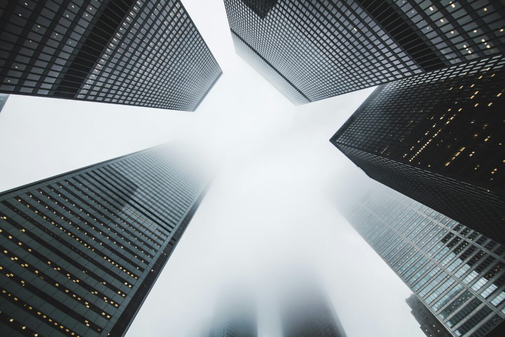 Ground-up view of a cloudy sky and haze between grey skyscrapers, representing the fraud litigation services provided by Milosevic & Associates in Toronto, including mortgage fraud.