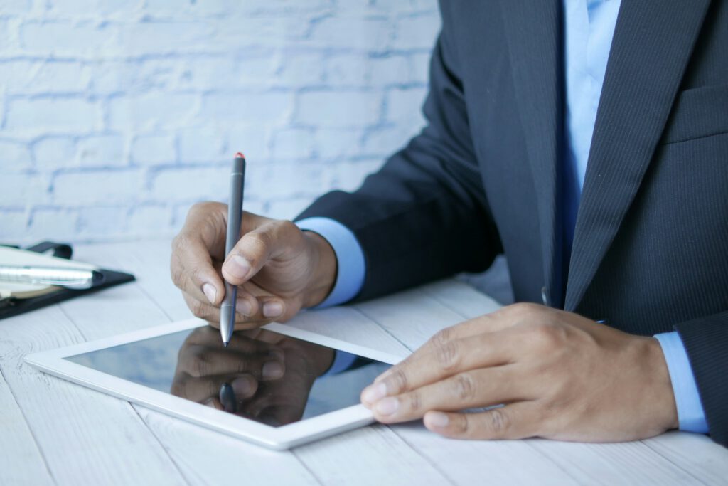 A businessman reviewing documents with a stylus on a tablet, representing the asset recovery services provided by the Toronto fraud litigation lawyers at Milosevic & Associates.