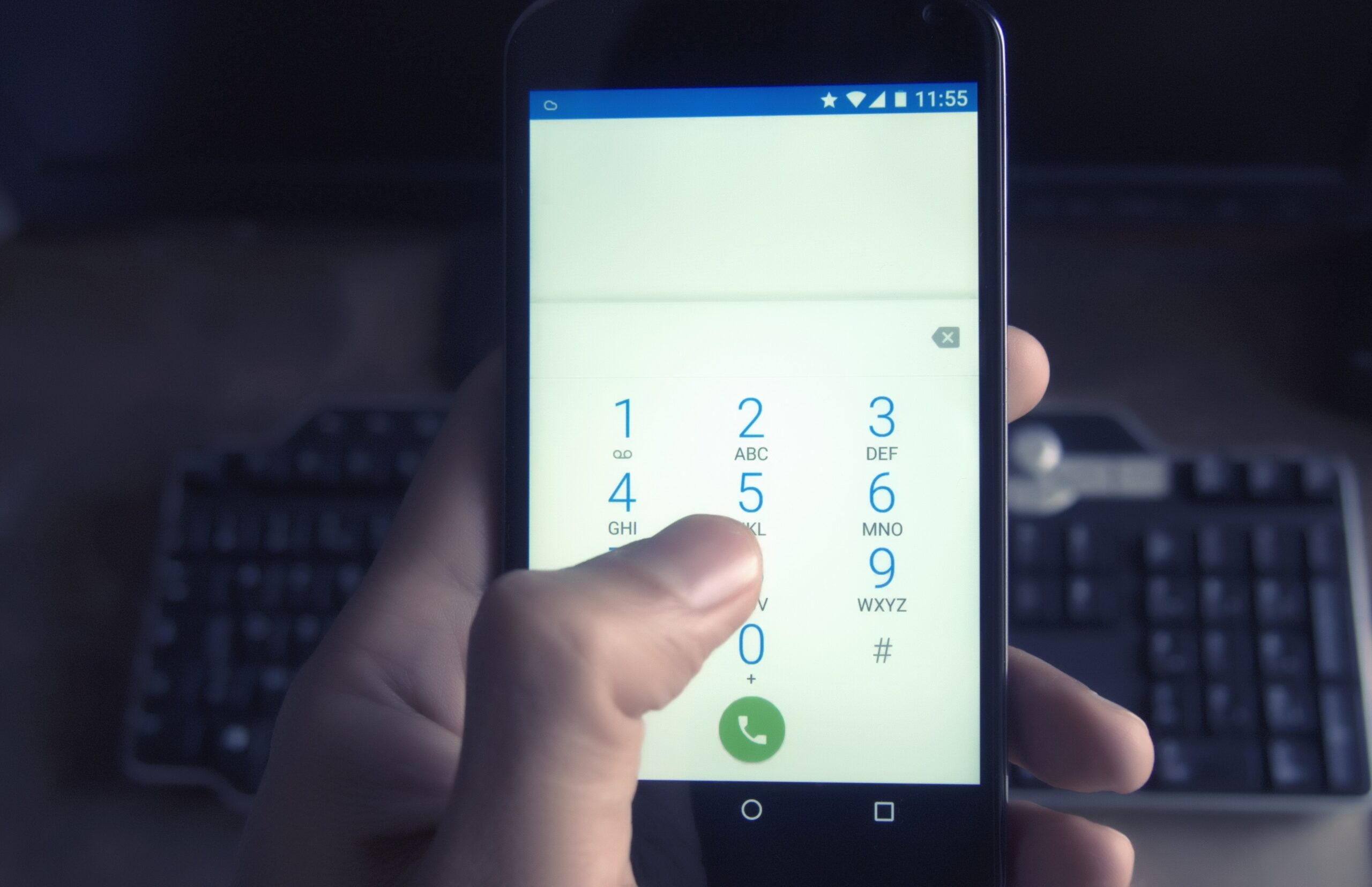 close up of a hand dialling a number on a touch screen cell phone