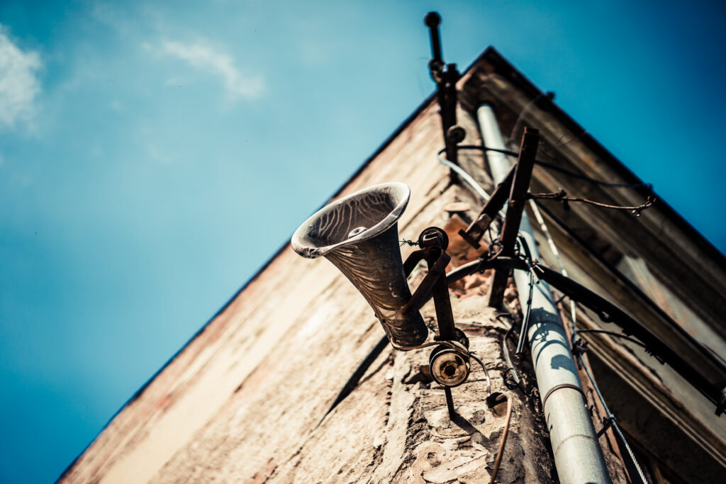 Old loudspeaker attached to brick building