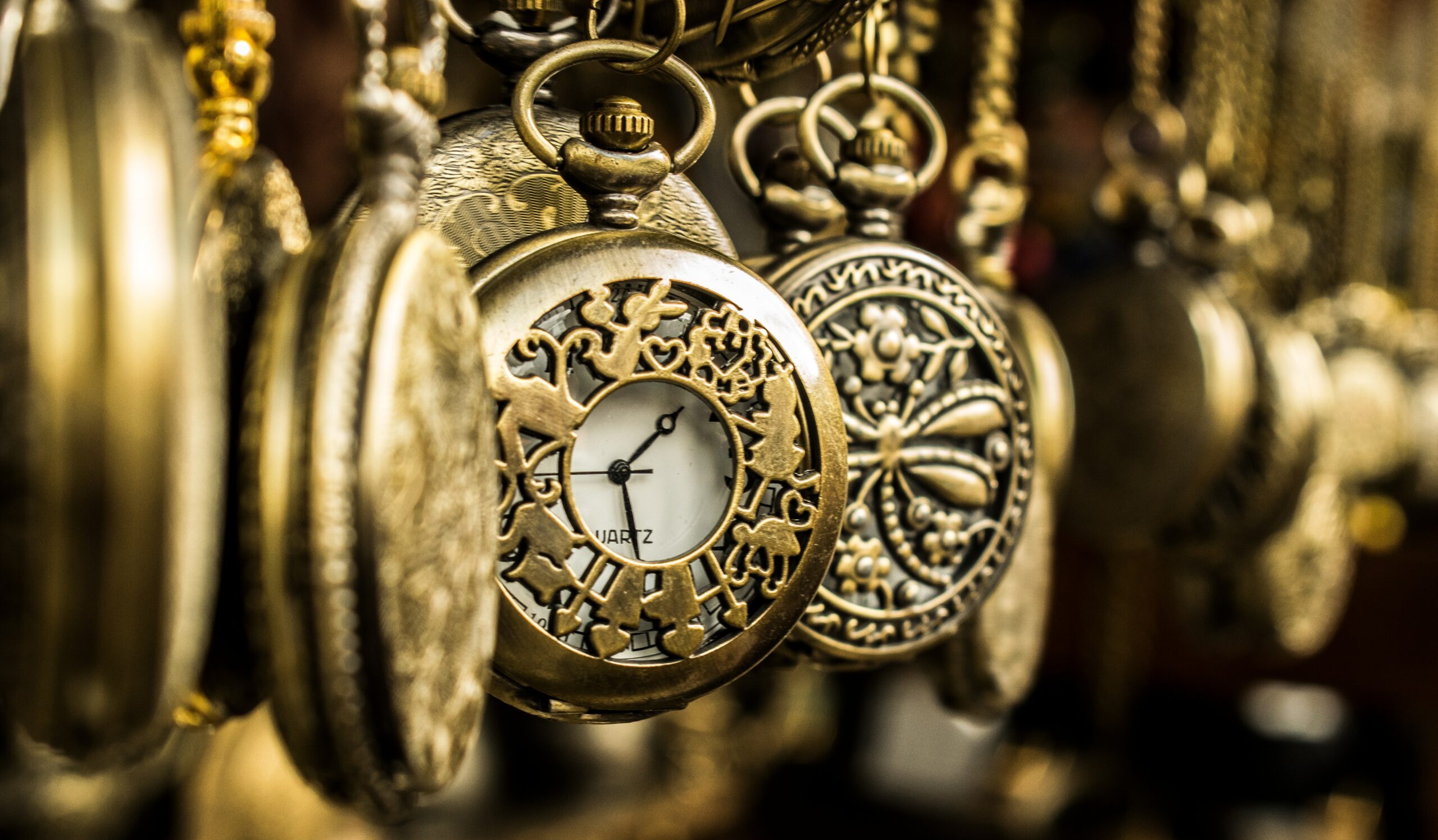a group of ornate brass pocket watches hanging by chains, with one clockface visible, representing time sought in an adjournment