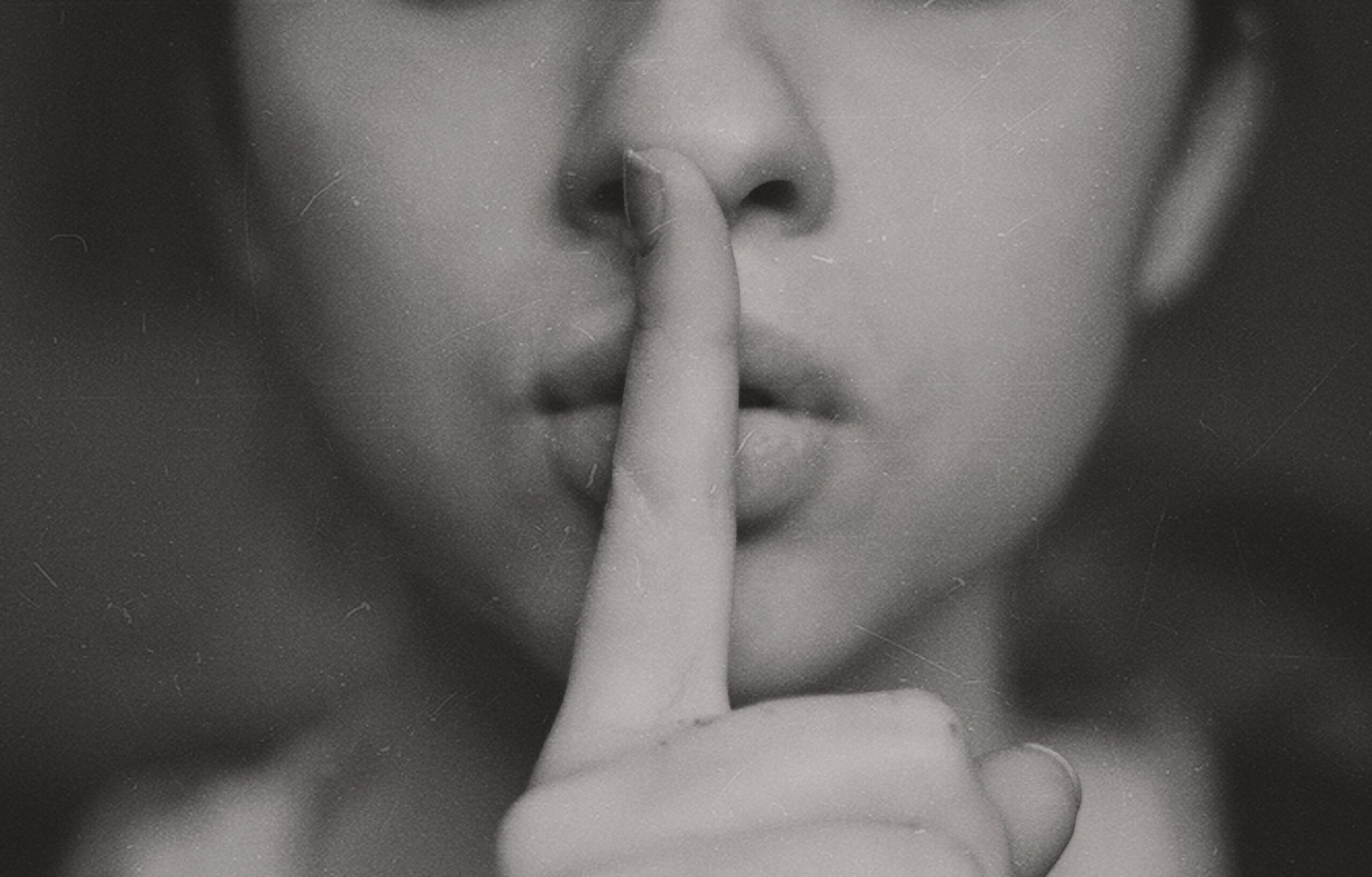 a woman holding her finger to her lips as if to represent staying silent