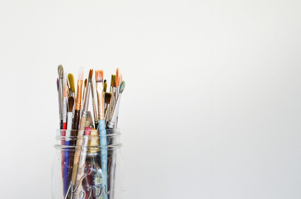 A jar of paintbrushes, representing a painting on canvas