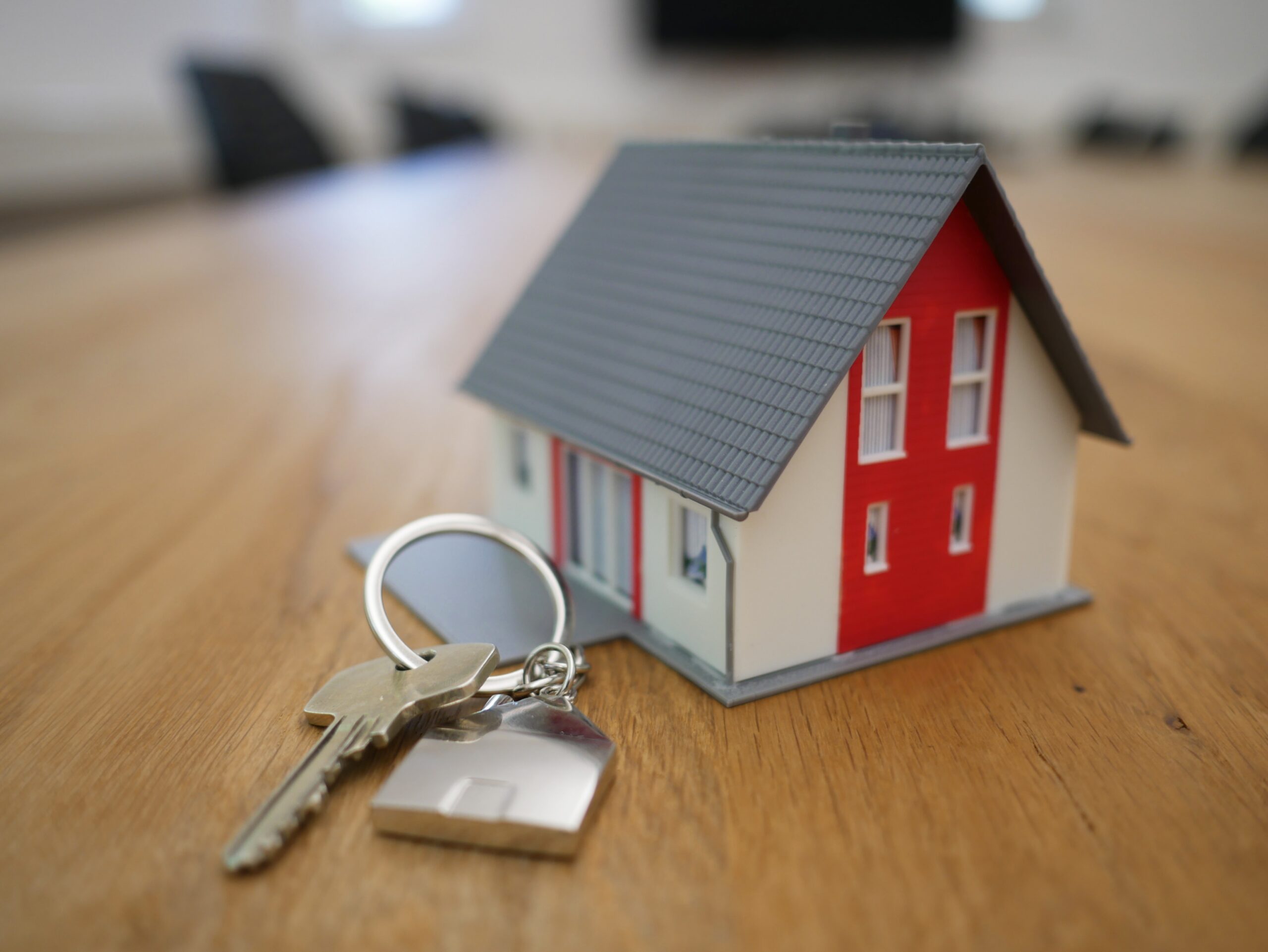 a small model house beside a key on a keychain