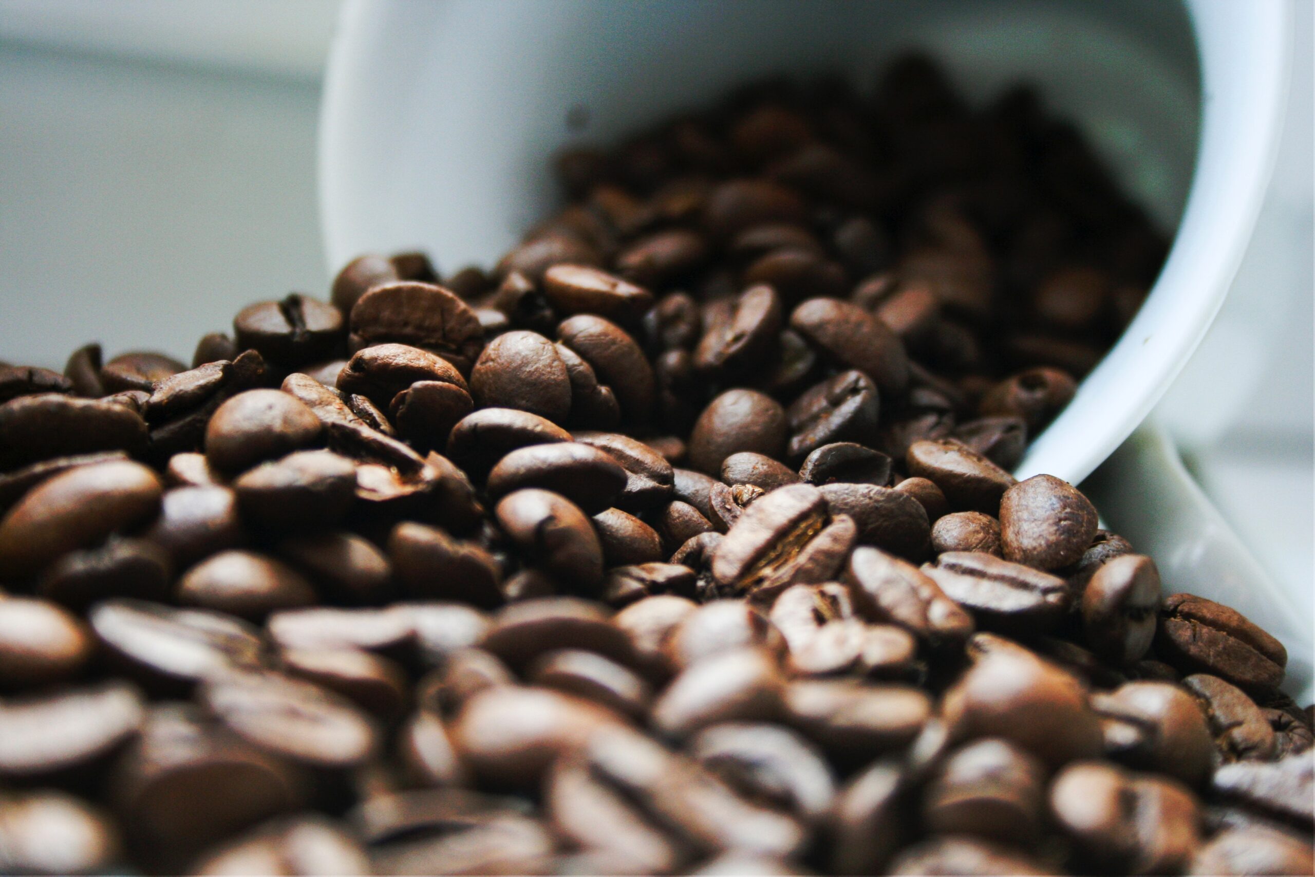 A white mug with coffee beans spilling out representing a coffee shop franchise at the heart of an application for stay pending arbitration