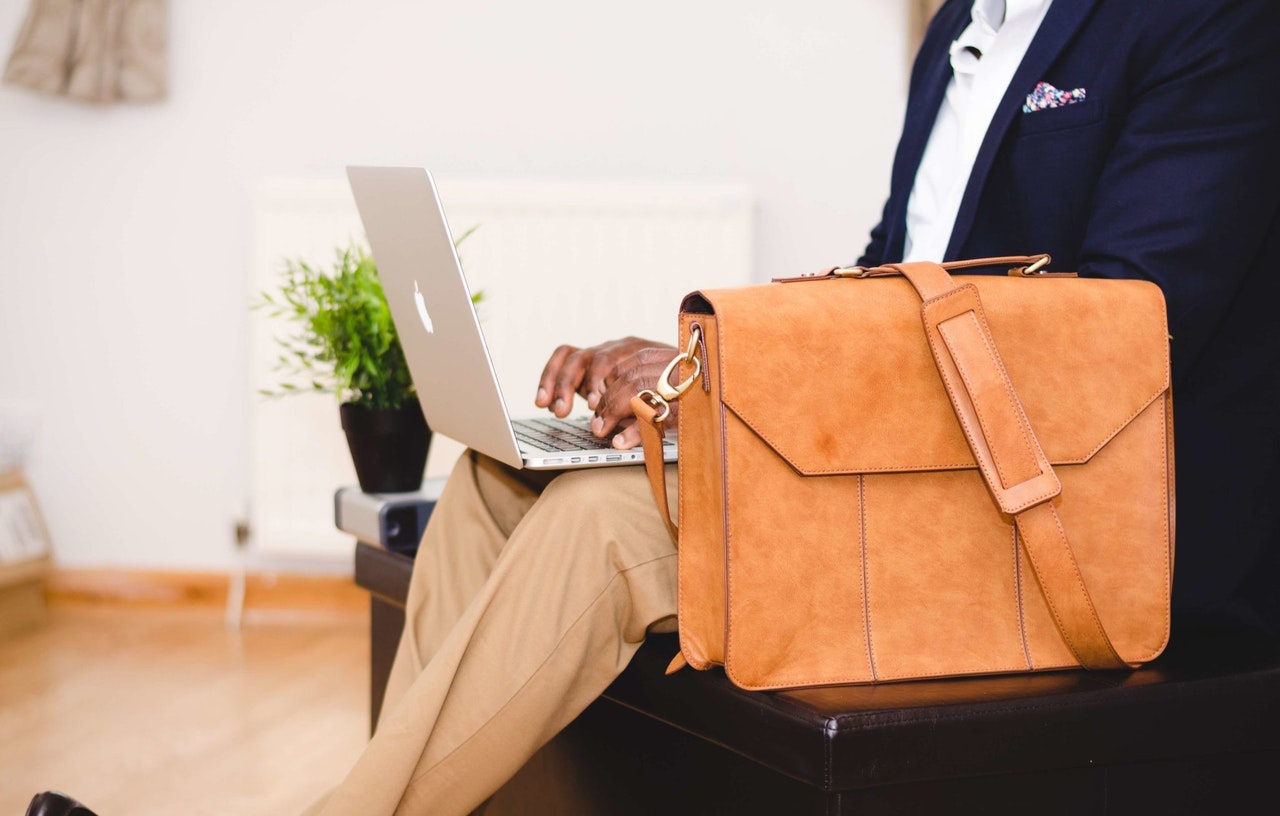 A man on a laptop with a briefcase representing a self-represented litigant