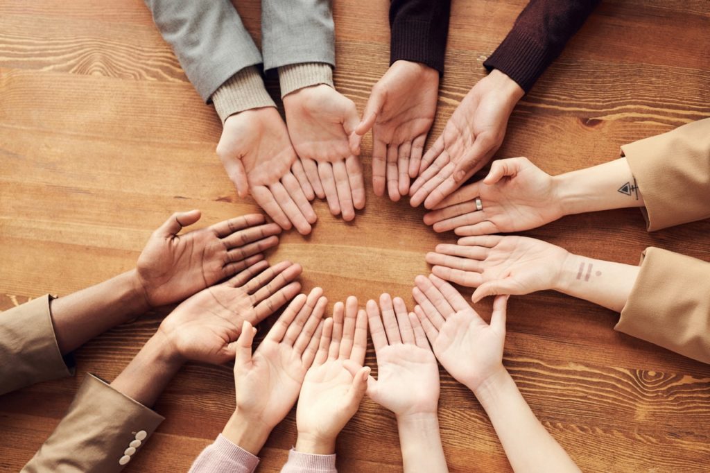 A group of hands palm up on a table representing a variety of creditors entitled to payment in the event of a bankruptcy
