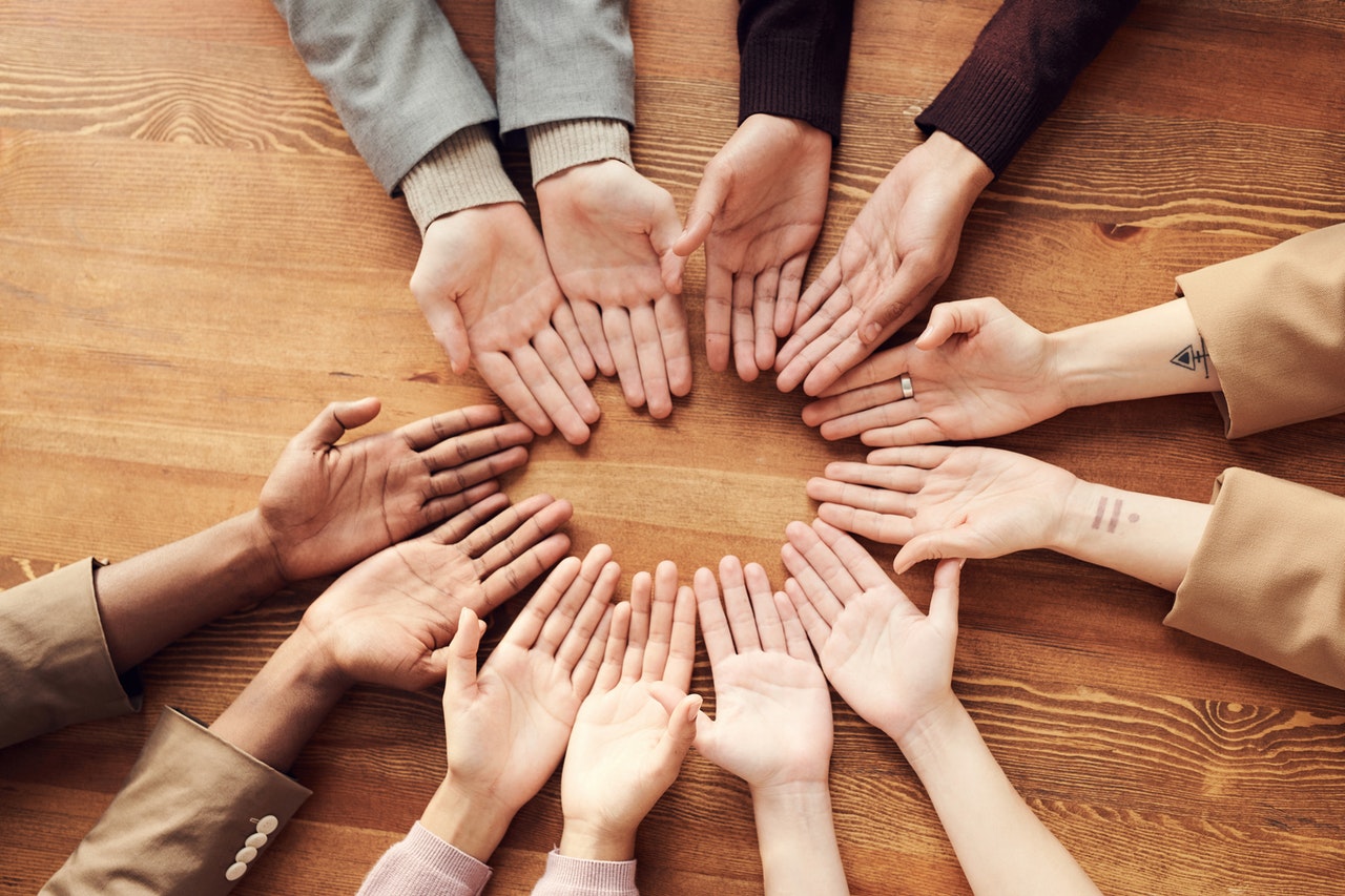 A group of hands palm up on a table representing a variety of creditors entitled to payment in the event of a bankruptcy