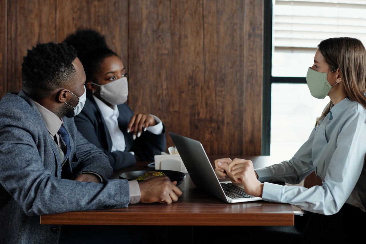 A business meeting with covid masks representing the impact of covid on mutually adverse effects clauses