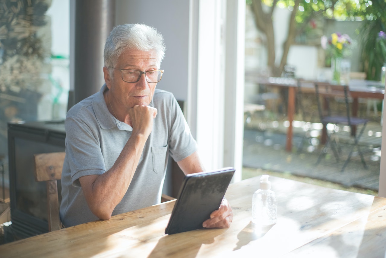 An older man looking at a tablet representing new obligations for financial advisors who represent senior clients
