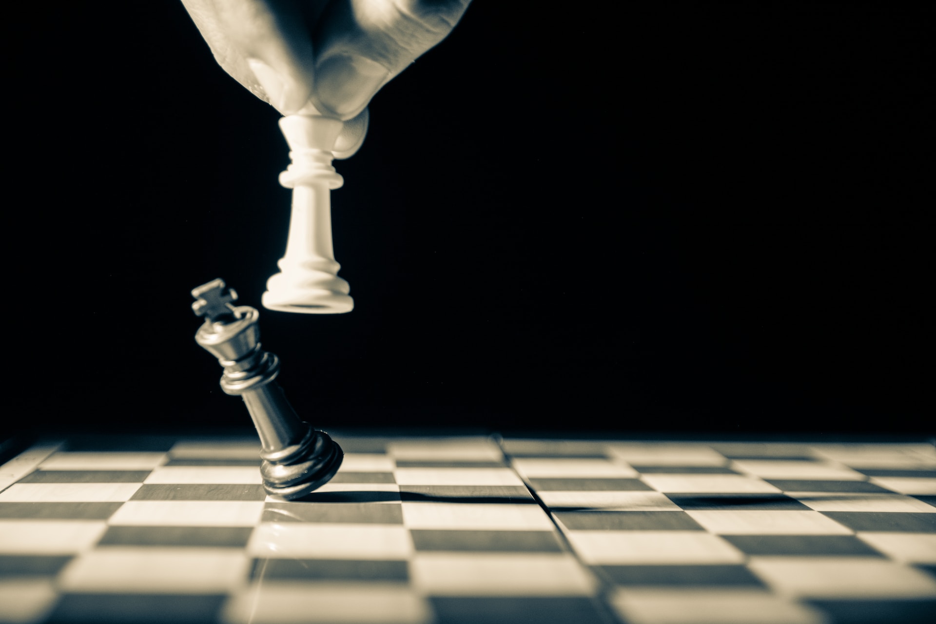 A white pawn knocking over a black King on a chessboard, representing partisanship in politics