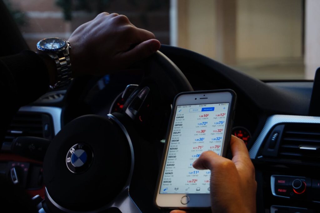 a person in a bmw looking at cryptocurrency statistics on their smartphone