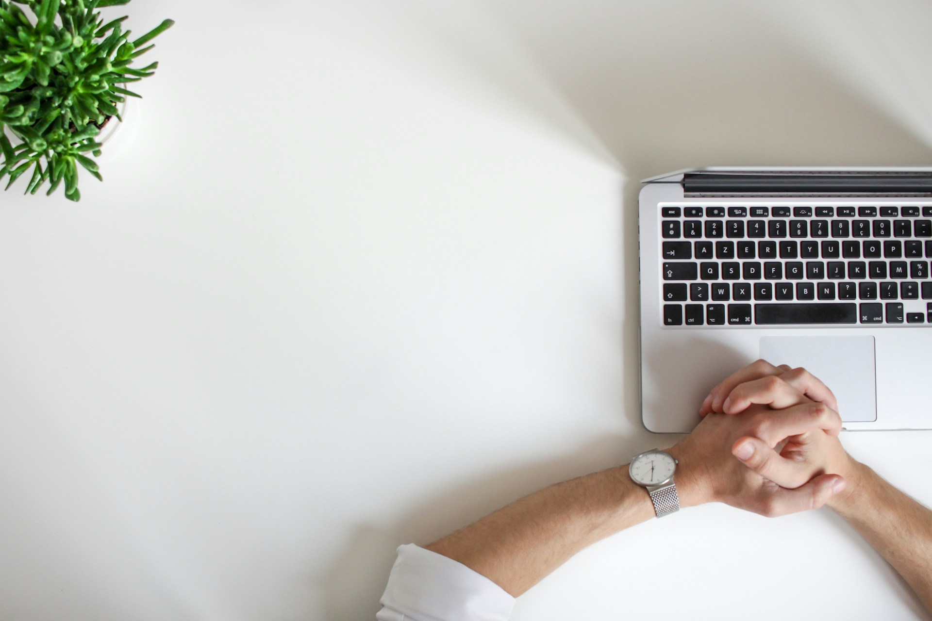 person wearing watch and white shirt sitting with laptop