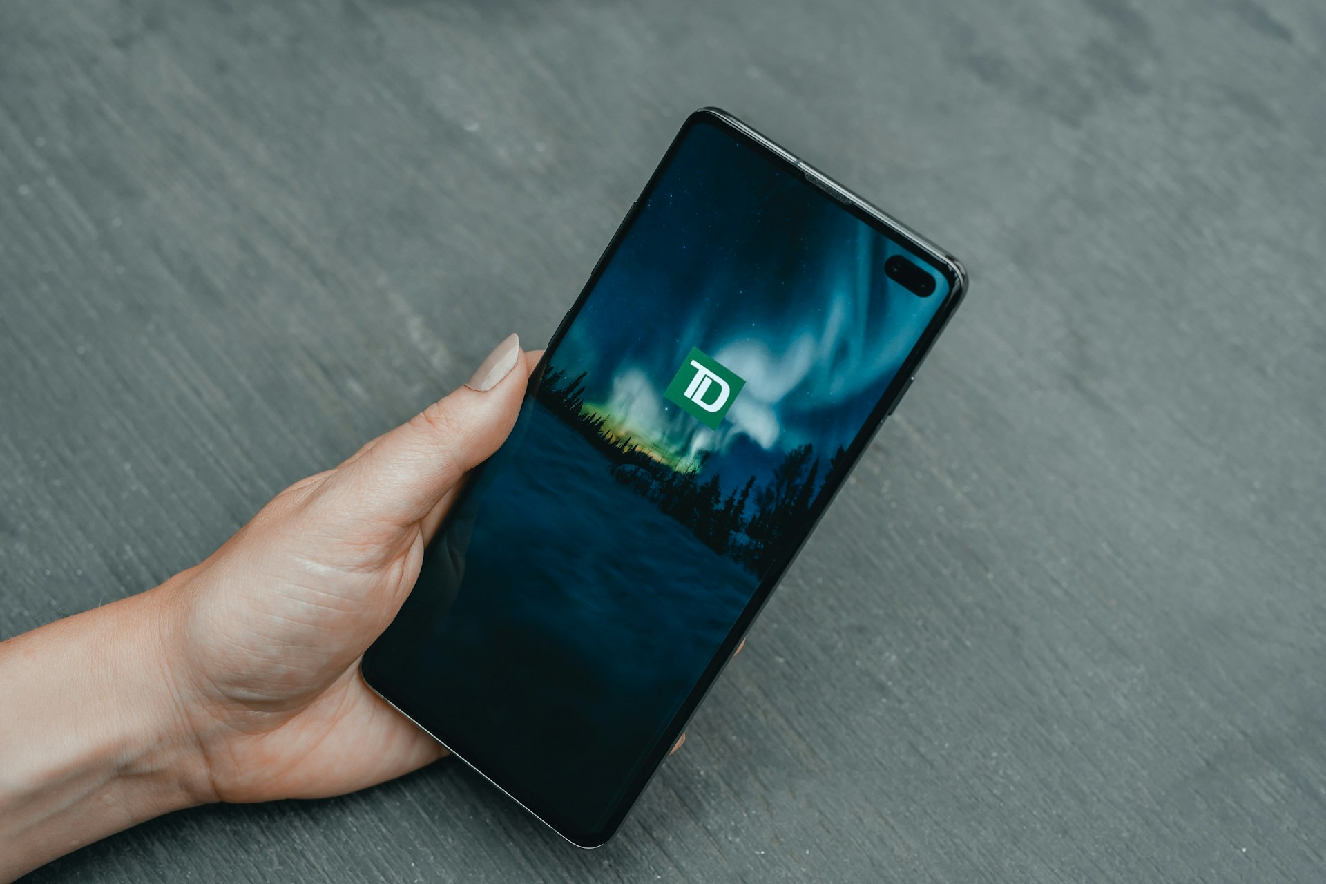 a person holding cell phone with TD logo displayed