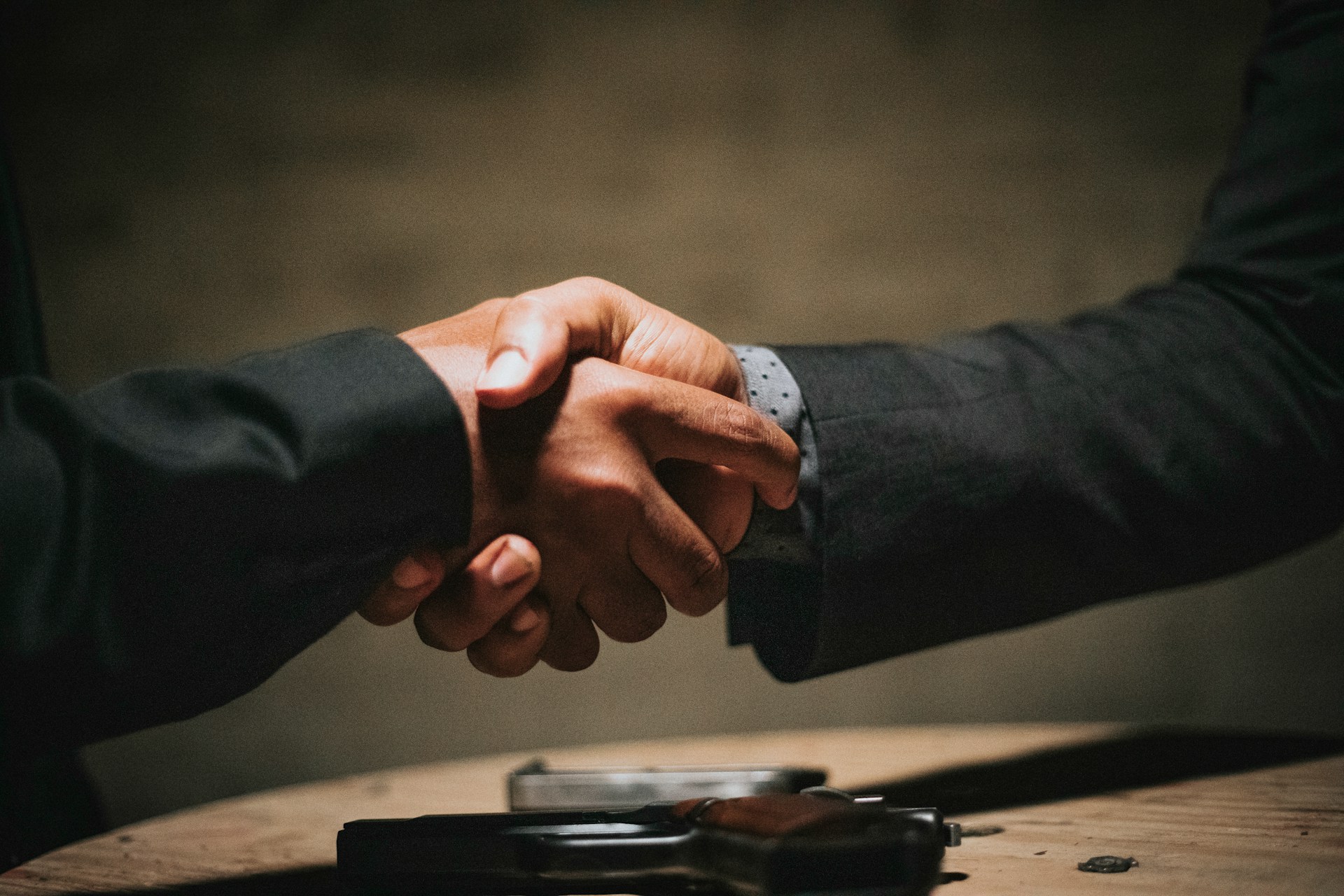 two people shaking hands over table