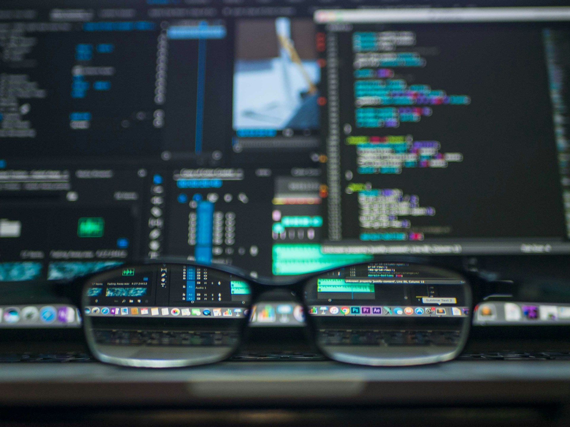 Multiple computer screens covered in complex coding language, as seen through a pair of eyeglasses, representing civil fraud