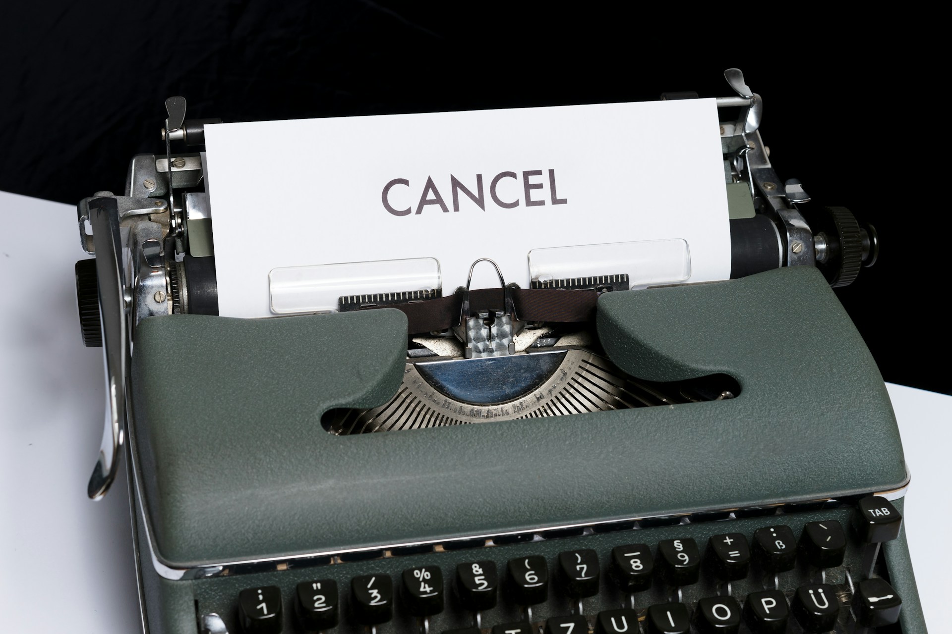 A close-up of a vintage typewriter with the word "CANCEL" typed in black on a white sheet of paper.