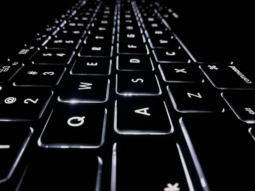 A close-up, side-angle of a black back-lit keyboard, representing Norwich Orders and defamation.