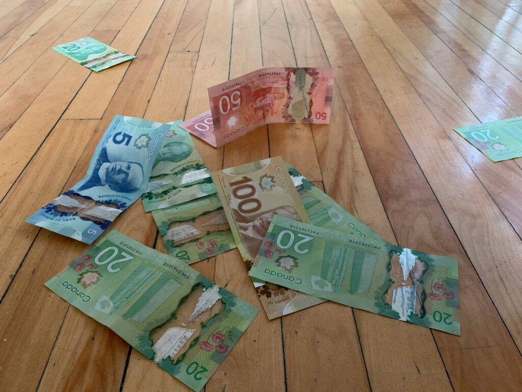 Five, twenty, fifty, and one-hundred-dollar bills scattered over a wooden floor, representing Securities Act Disgorgement.