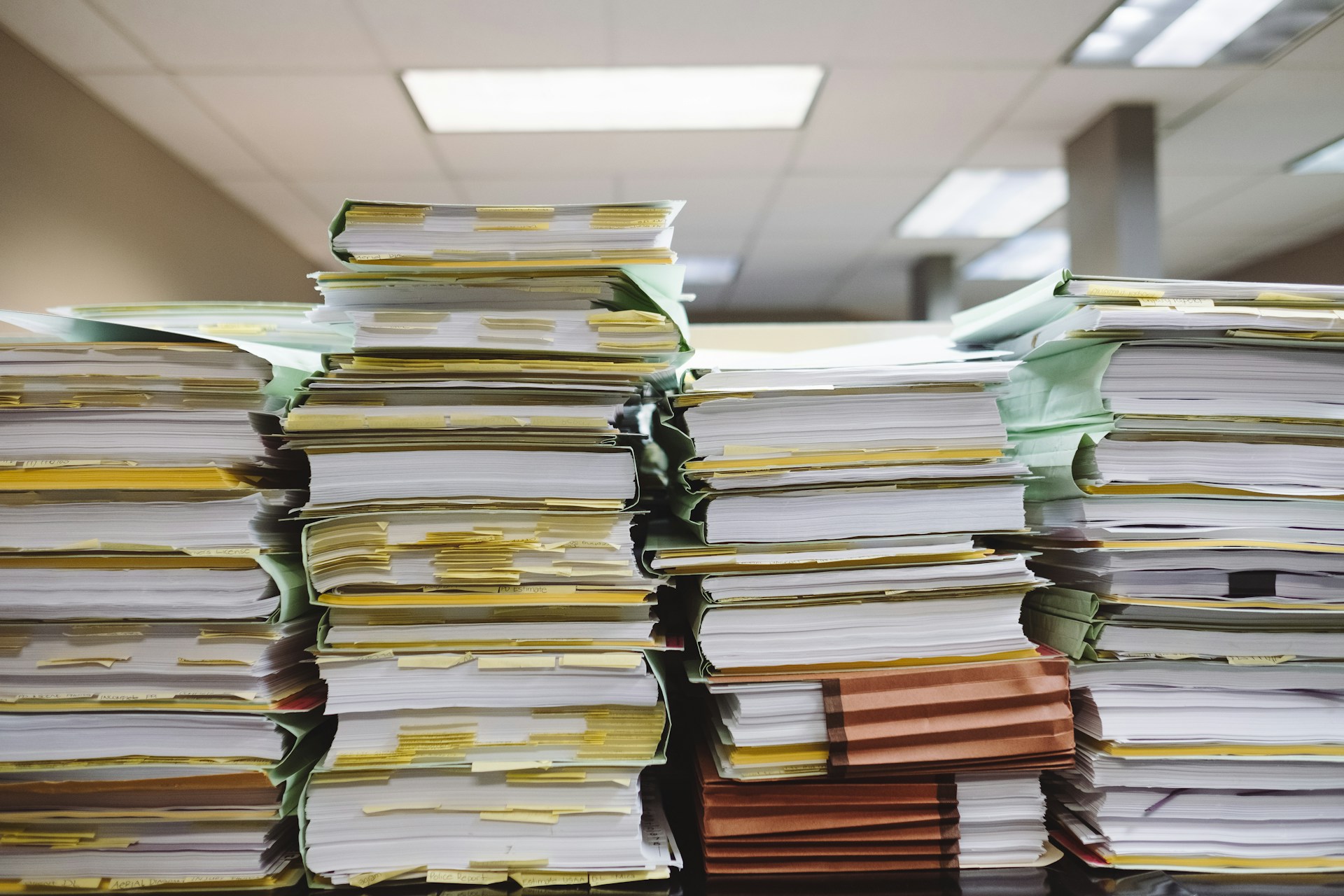 Four stacks of thick file folders on a desk in an office, representing audited corporate financial records.