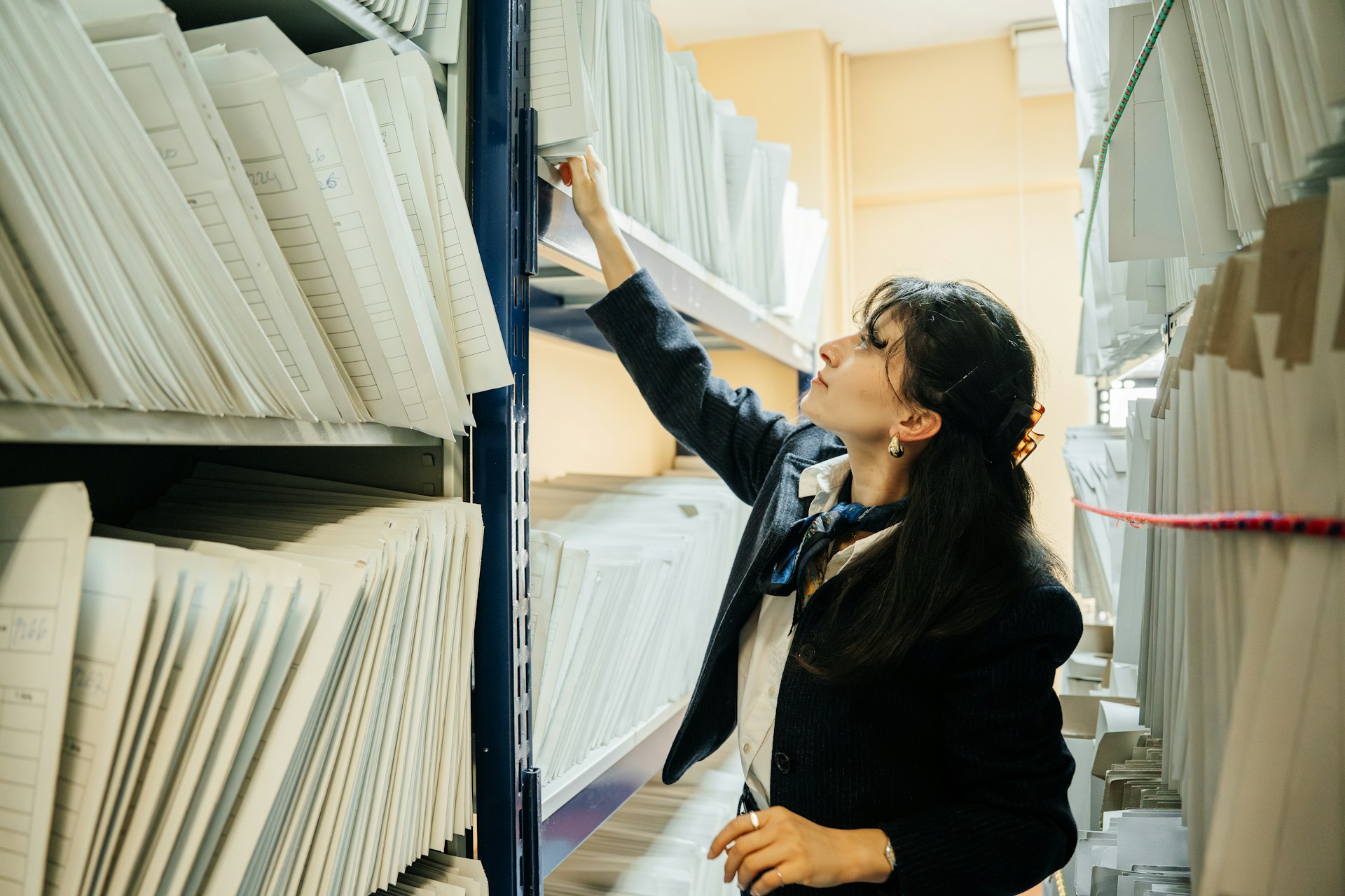 A woman organizing extensive shelves of files, representing corporate records and family business shareholder disputes in Toronto