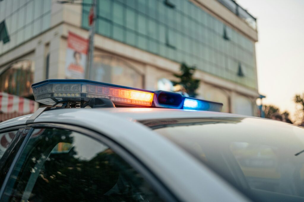 Light on top of a police car with a business in the background, representing employment fraud charges.