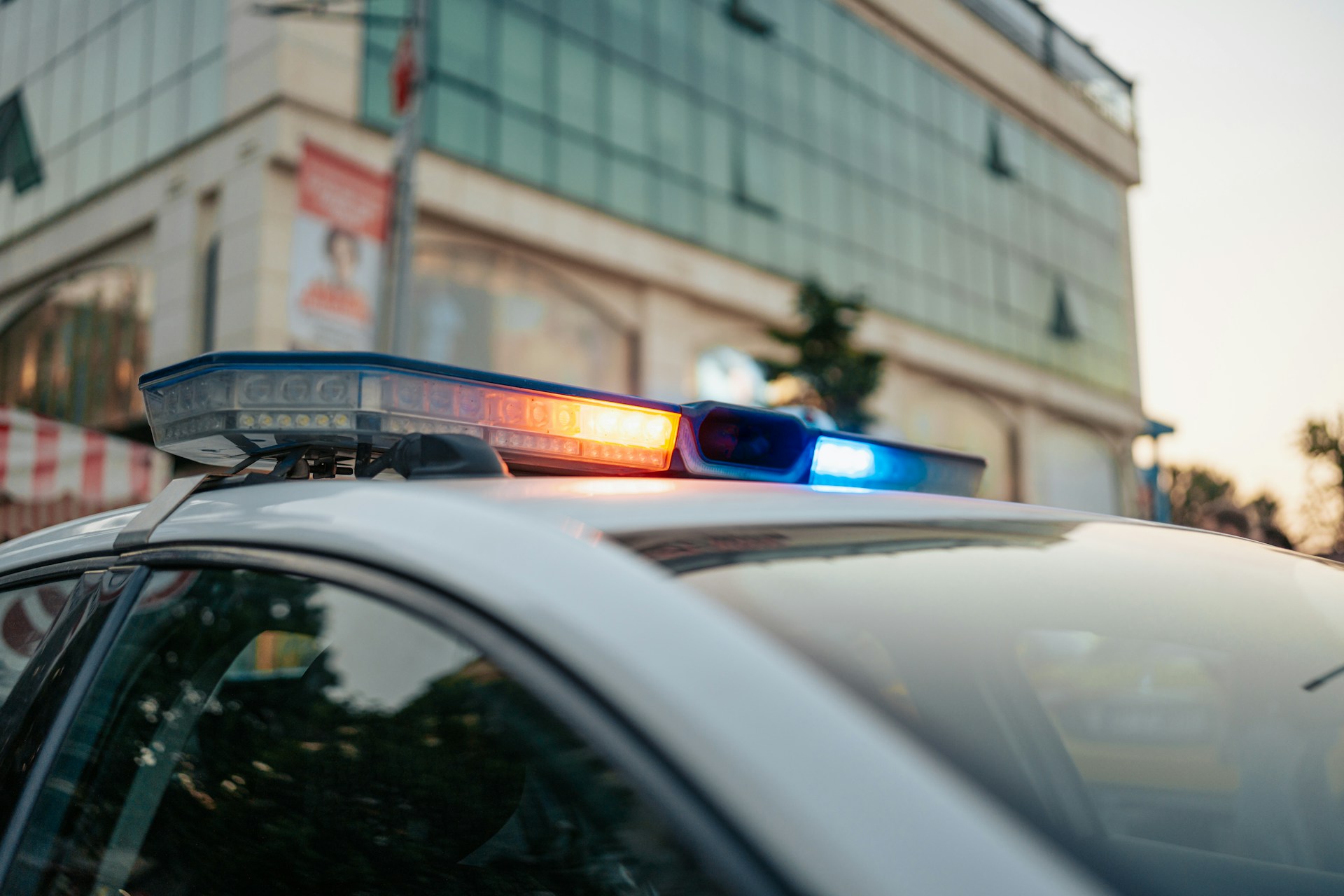 Light on top of a police car with a business in the background, representing employment fraud charges.
