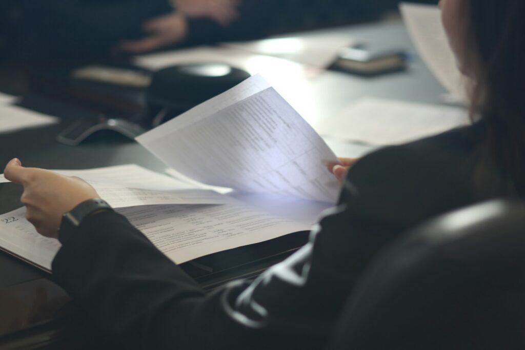 A professional female lawyer reviewing a table full of documents, representing the appellate lawyers at Milosevic & Associates, representing clients before the Ontario Divisional Court in Toronto and across Ontario.