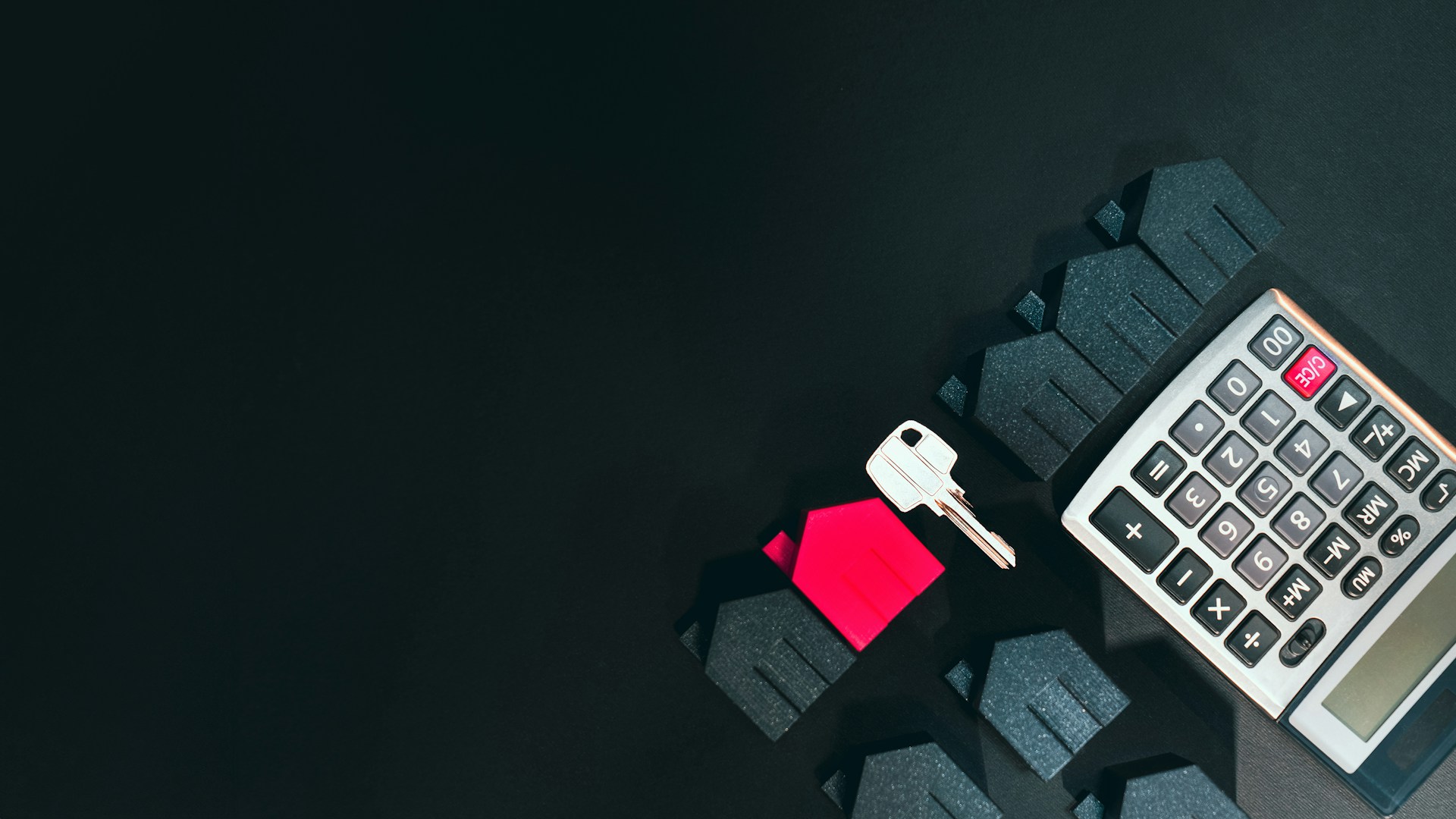 A calculator, house key and home icons with a black background depicting mortgage fraud in Ontario.