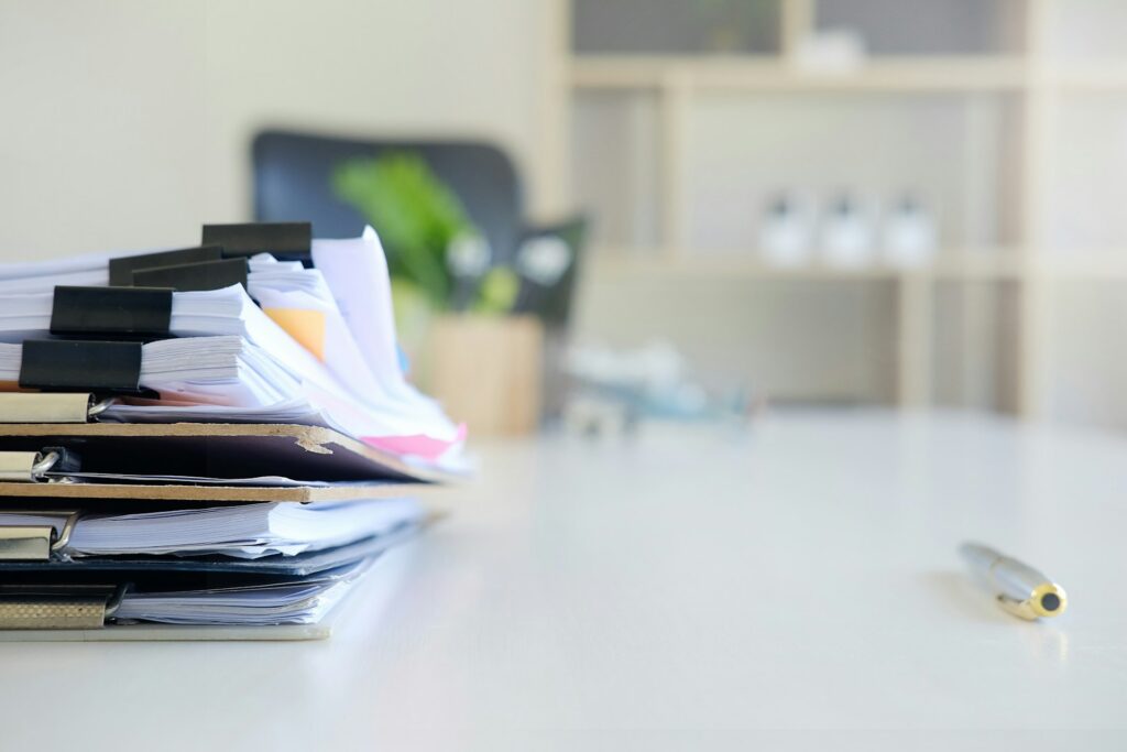 A stack of papers with paper clips sitting on a table representing invoice fraud in Ontario.