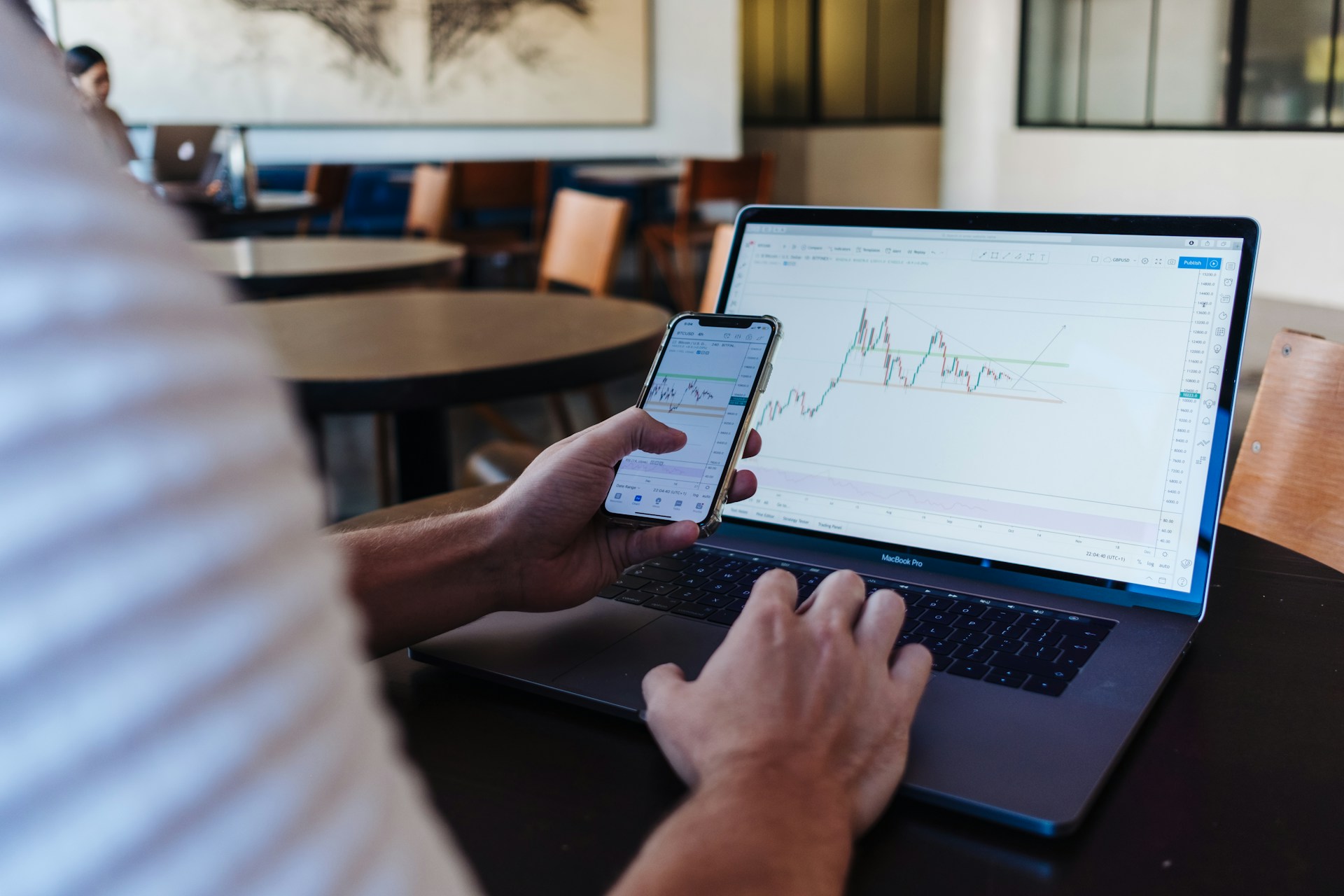 A person using smartphone and mac book looking at a stalk market representing securities fraud in Toronto.