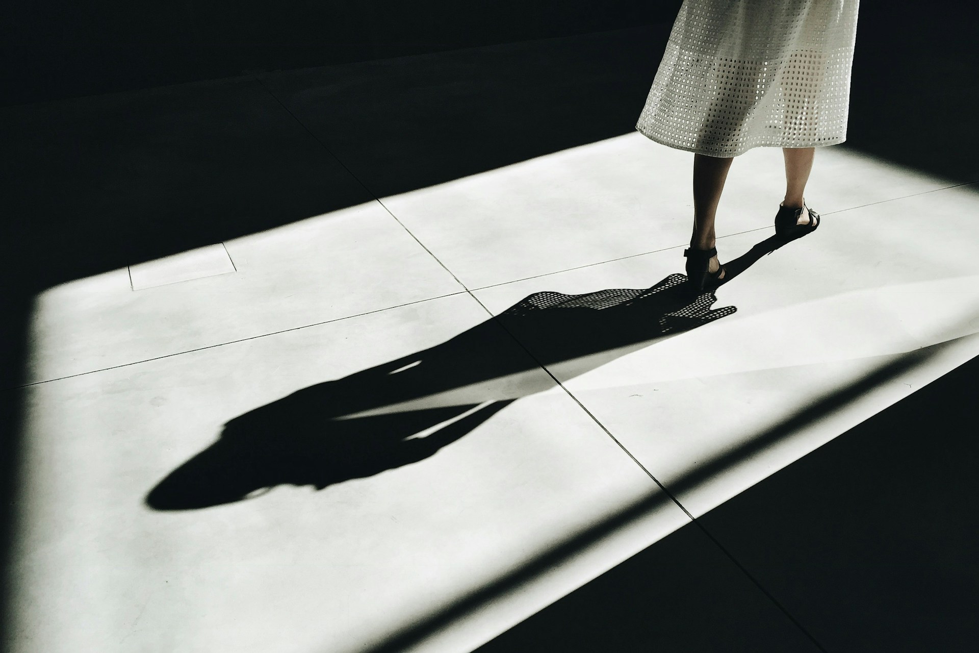 A woman in a white dress and black shoes walking with shawdow behind her, representing shawdow directors and liability in Ontario commercial litigation matters.