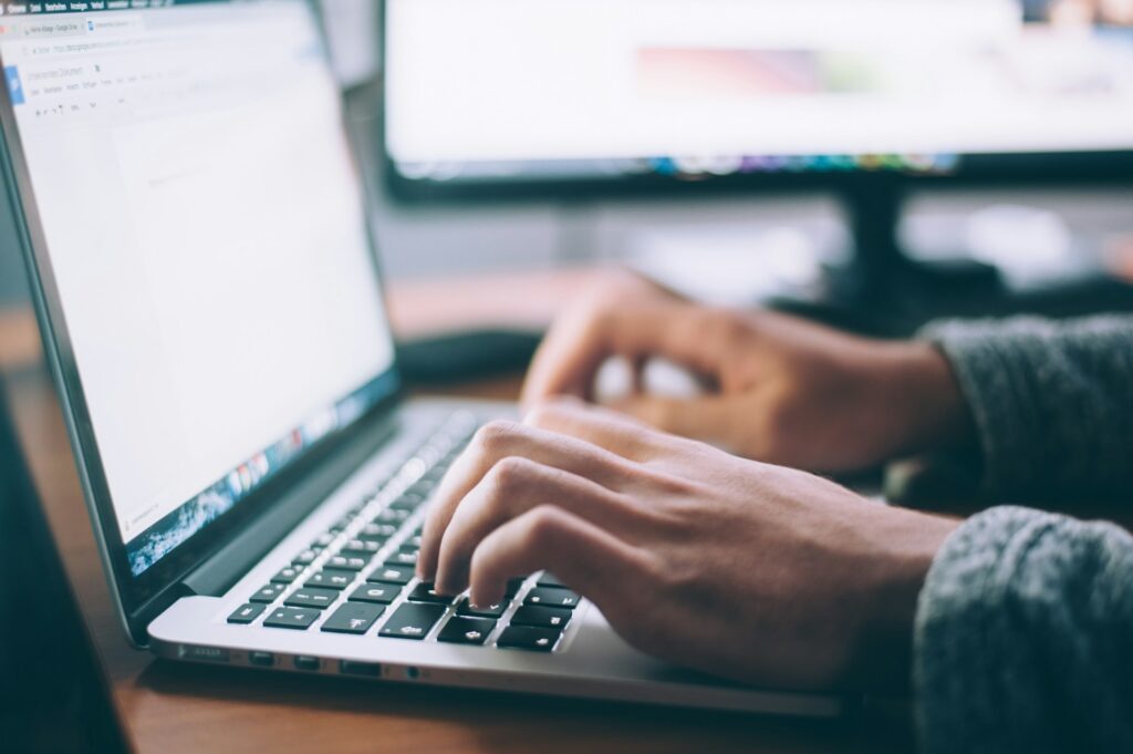 A close-up of hands typing on a laptop keyboard with a blurred computer monitor in the background, representing spoilation in commercial litigation.