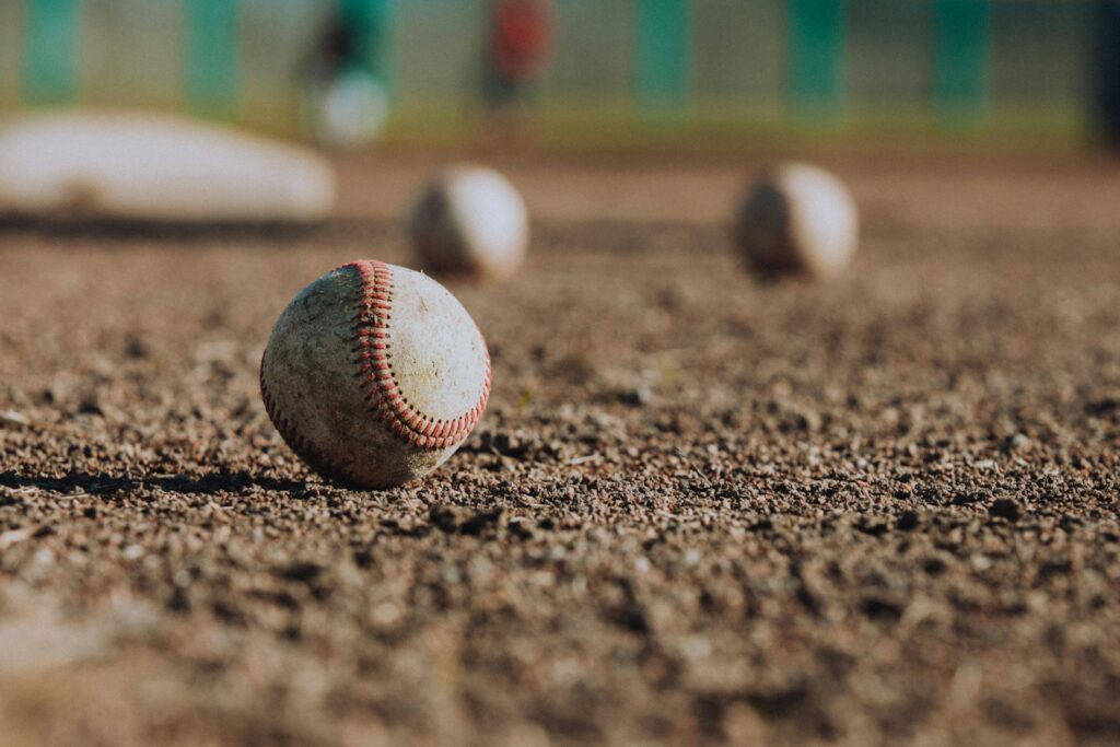 Three baseballs on the ground in a baseball diamond, representing the recent ontario youth baseball fraud allegations of former Major League Baseball player Richard Butler and his wife, Michelle Butler.